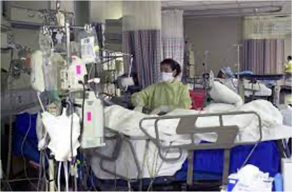 Nurse standing next to a patient in a hospital bed in ICU.