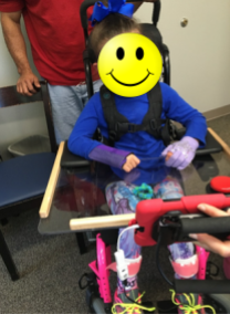 Shoulder straps holding a young girl in an upright position in a wheelchair